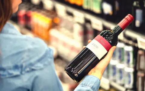 Kobieta wybiera wino, zastanawiając się, czy to jej osobisty wysokofunkcjonujący alkoholik test.