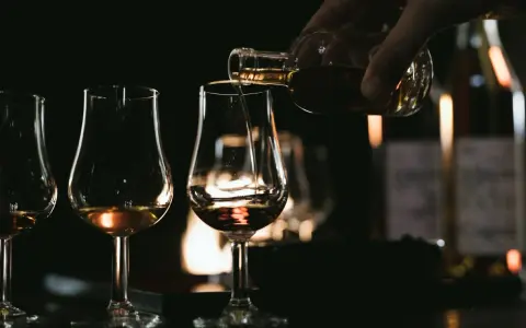 Degustacja koniaku: nalewanie bursztynowego trunku do kieliszków. Poznaj tajniki, jak pić koniak, by docenić jego głębię.