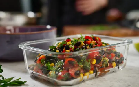 Frischer schwarze bohnen salat mit Mais, Tomaten und Kräutern in einer Glasbox.