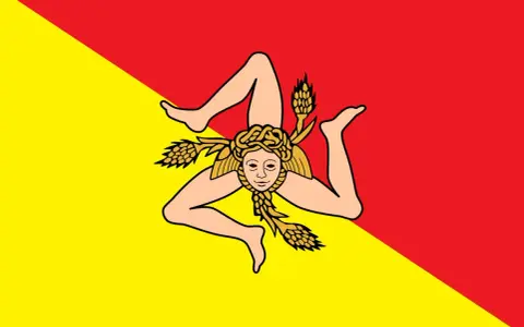 Lo stemma della Sicilia, la Trinacria, con la testa di Medusa e tre spighe di grano, su sfondo diviso in giallo e rosso.