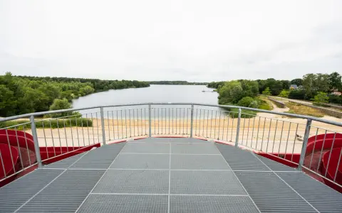 Blick vom Aussichtsturm auf den Offlumer See mit Sandstrand und grünen Ufern.