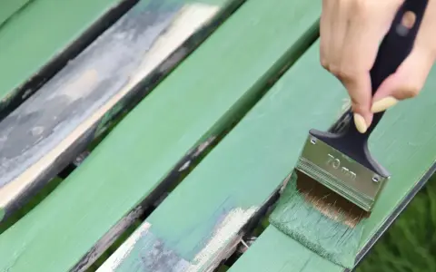 Malowanie ławki na zielono. Szukasz idealnej farby do plastiku na zewnątrz? Pędzel z zieloną farbą odnawia stare deski.