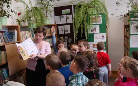 Nauczycielka czyta dzieciom książkę, tworząc inspirujące lekcje biblioteczne scenariusze. Dzieci słuchają z uwagą.