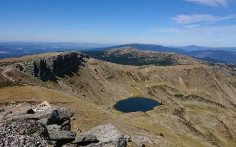 Paisaje montañoso con un lago azul en un valle, ideal para senderismo Soria.