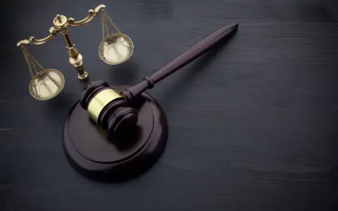 Wniosek o zamianę prac społecznych na potrącenie z wynagrodzenia wzór. Młotek sędziowski i waga sprawiedliwości na ciemnym tle.