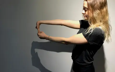 Jeune femme faisant un étirement du poignet, geste clé pour la rééducation de l'épitrochléite et réduire le temps de guérison.