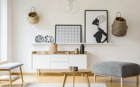 Un mueble blanco resalta sobre una pared clara, complementado con cestas de mimbre y arte africano. El color de pared para muebles blancos es neutro y elegante.
