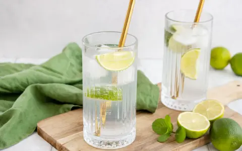 Erfrischende Drinks: Zwei Gläser mit Eis, Limettenscheiben und goldenen Strohhalmen. Perfekt zum **Wodka mischen** an einem warmen Tag.