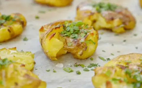 Smashad potatis, gyllene och krispiga, toppade med färsk persilja. Perfekt tillbehör som smälter i munnen.