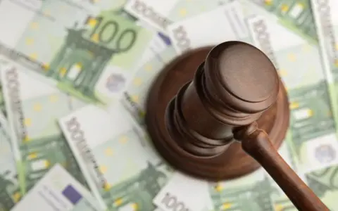 Młotek sędziowski na tle banknotów 100 euro.