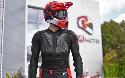 Motocyklista w kasku i ochraniaczach. Kurtka z membraną chroni przed wiatrem i deszczem, zapewniając komfort.
