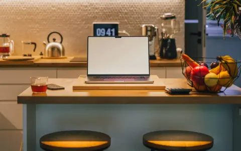 Ein Laptop steht auf einer Küchentheke neben Obst und einem Glas Tee. Vielleicht fragst du dich, was Bixby ist – ein digitaler Assistent, der dir bei vielen Dingen helfen kann.