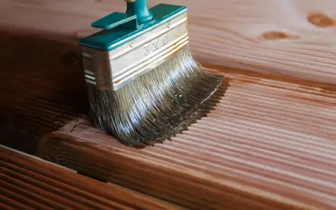 Application d'une lasure sur des lames de bois de douglas. La brosse dépose le produit sur le bois, le protégeant et le sublimant.