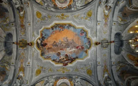 Plafond orné de fresques célestes, un exemple de style **rococo def.**, avec des anges, des chevaux et un soleil éclatant.
