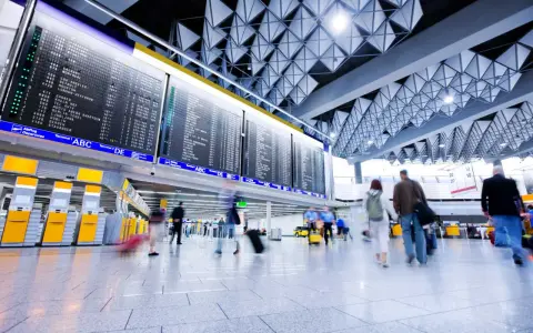 Lotnisko, tablica odlotów, ludzie z bagażami. "Boarding co to?" - to informacja o wejściu na pokład samolotu.