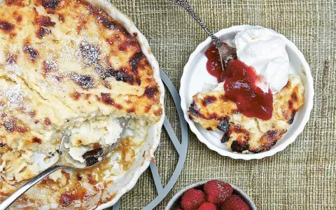 En gyllene falsk ostkaka med krispiga kanter, serverad med vispad grädde, sylt och färska hallon.