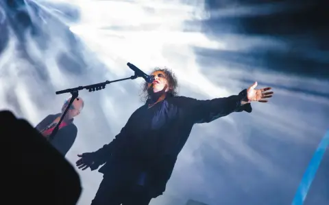 Robert Smith sjunger med utsträckta armar under The Cure i Stockholm.
