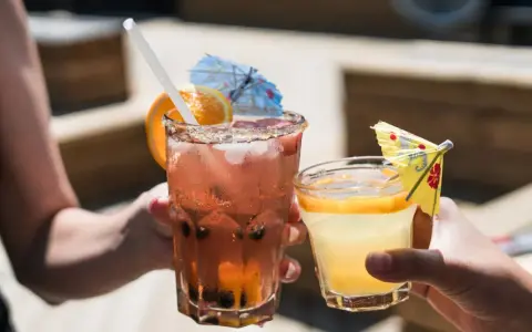 Dwa orzeźwiające drinki, jeden różowy z owocami i pomarańczą, drugi żółty z plasterkiem pomarańczy. Idealne na letnie popołudnie, może z dodatkiem białego wina.