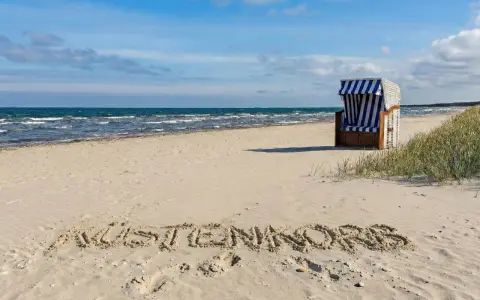 Der Juliusruh Strand lädt mit einer Strandmuschel und dem Schriftzug "KUSTENKORS" im Sand zum Verweilen ein.