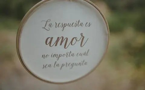 Bordado con "La respuesta es amor, no importa cuál sea la pregunta", ideal para frases cortas para felicitar bodas.
