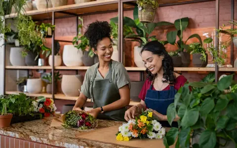 Deux fleuristes souriantes créent des bouquets. Un métier artistique bien payé qui embellit le quotidien.