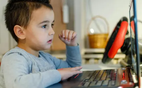 Chłopiec z zaciekawieniem ogląda na laptopie materiały o biologii dla dzieci.