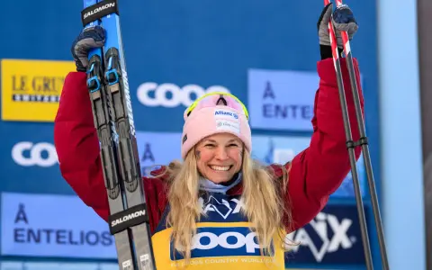 Uśmiechnięta narciarka z nartami w górze, świętuje sukces w biegach narciarskich. Klasyfikacja generalna FIS Cross Country World Cup.