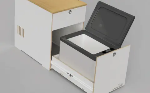 En kylbox med kompressor testas i en vit möbel med trädetaljer. Locket är öppet och lådan är utdragen.