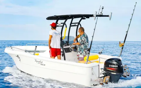 Deux hommes sur un bateau de pêche, avec un roll bar pour bateau, profitent de la mer bleue.