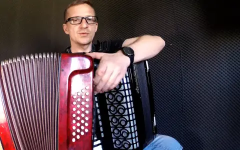 Mężczyzna w okularach uczy się grać na akordeonie. Lekcje gry na akordeonie dla dorosłych to świetny pomysł na rozwijanie pasji.