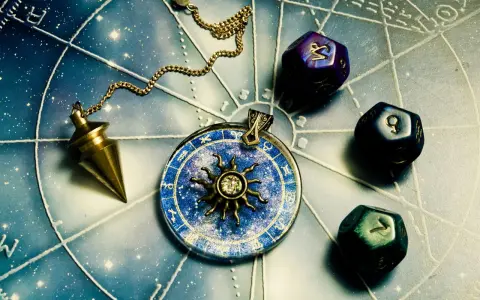 Wahadło i kostki do gry z symbolami zodiaku. Koziorożec jaki żywioł? Ziemia, symbol stabilności i determinacji.