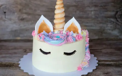 Ein magischer einhorn kuchen mit pastellfarbener Glasur, einem gedrehten Horn und süßen Wimpern.