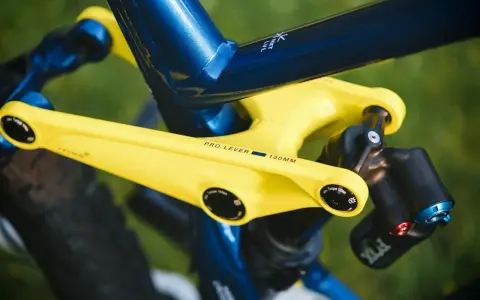 Żółte ramię przerzutki z napisem "PRO LEVER 180MM" na tle niebieskiej ramy roweru. To połączenie zapewnia doskonały reach i stack, a także wzrost wydajności.