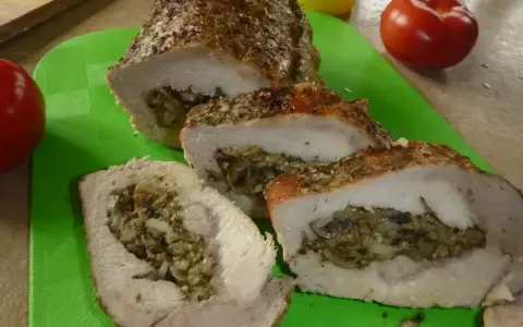 Pyszny kotlet husarski, pieczony z ziołami i nadzieniem grzybowym, pokrojony na desce.