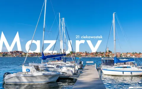 Żaglówki cumujące w porcie na Mazurach, Polska. W tle malownicze miasteczko nad jeziorem.
