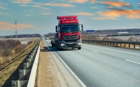 Czerwona ciężarówka jedzie autostradą. Ubezpieczenie kabotażowe zapewnia spokój podczas międzynarodowych transportów.