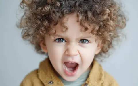 Niño de 1 año con rizos castaños, ojos marrones y expresión de enfado. Las rabietas son parte del desarrollo.