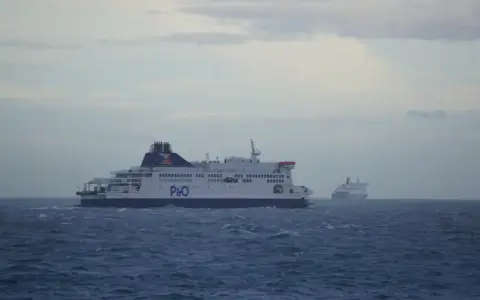 Dwa promy P&O płyną po wzburzonym morzu. Jeden z nich, bliżej, jest większy i wyraźniejszy. To widok z promu podczas przejazdu pod Kanałem La Manche.