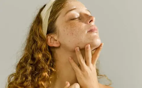 A young woman with freckles enjoys a relaxing skin care massage, her eyes closed in bliss.