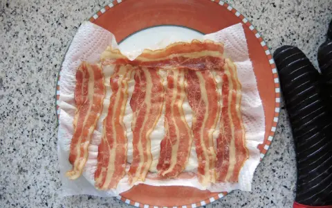Fertig zubereitetes Bacon auf Küchenpapier auf einem Teller. Schnell und einfach in der Mikrowelle gemacht.