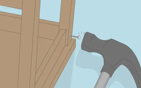 Un marteau s'apprête à frapper un clou dans la structure en bois d'un fauteuil qui grince.