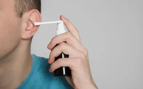 Mężczyzna aplikuje spray do ucha, łagodząc płyn w komórkach wyrostka sutkowatego.