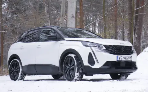 Biały Peugeot 3008 hybryda na śniegu, gotowy na zimowe przygody w lesie.