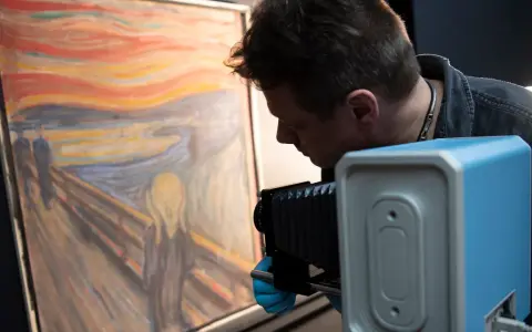 En man med blå handskar fotograferar "Skriet". Vem har målat skriet? Edvard Munch.