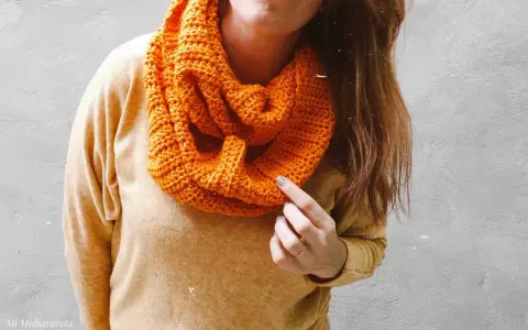 Persona con una bufanda naranja tejida, lista para el frío.