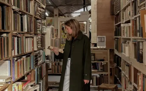 Kobieta w antykwariacie przegląda książki psychologiczne, które zmieniają życie. Wśród regałów pełnych literatury szuka inspiracji.