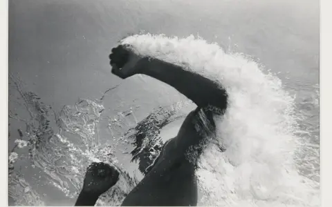 Underwater shot of a swimmer's arms and torso, creating a dramatic splash. The image captures the power and motion of a flip schulke.