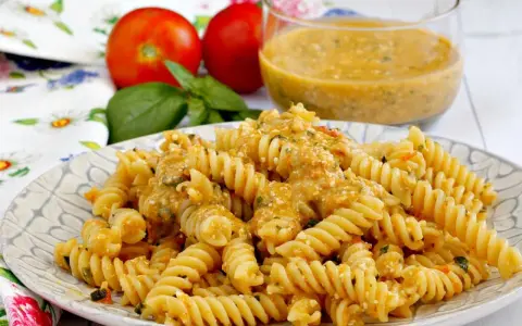 Fusilli conditi con una cremosa salsa di pomodoro e ricotta, guarniti con basilico fresco. Un piatto estivo perfetto.
