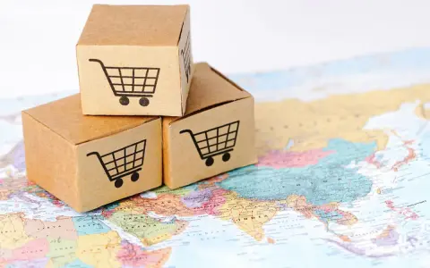 Trzy kartony z ikonami koszyków na zakupy na mapie świata. Symbolizują handel transgraniczny i globalny e-commerce.