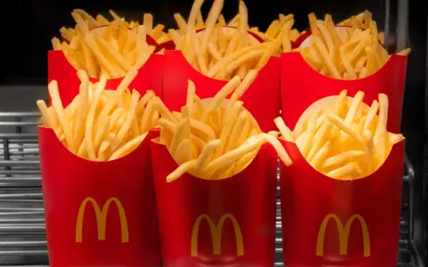 Rzędy czerwonych opakowań z logo McDonald's, wypełnione chrupiącymi frytkami. Zastanawiasz się, ile kosztują małe frytki w McDonald's?